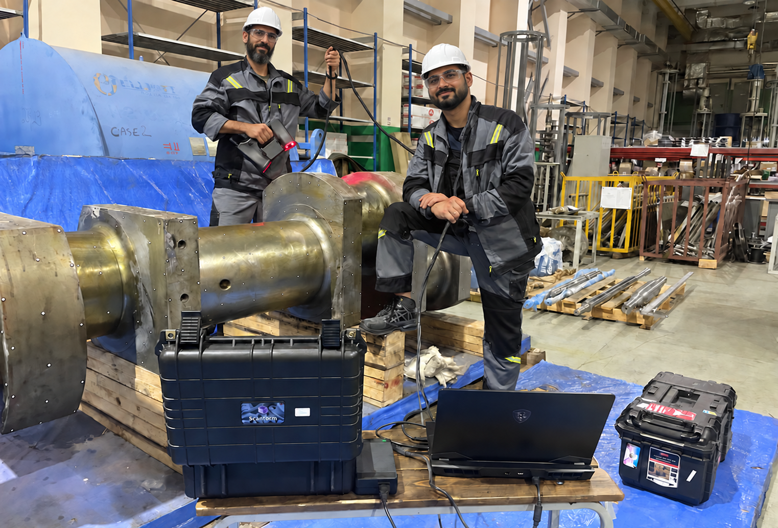 Two technicians in safety equipment working with an industrial component